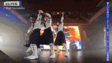 a group of people are dancing in front of a screen that says " maji yoroshiku "