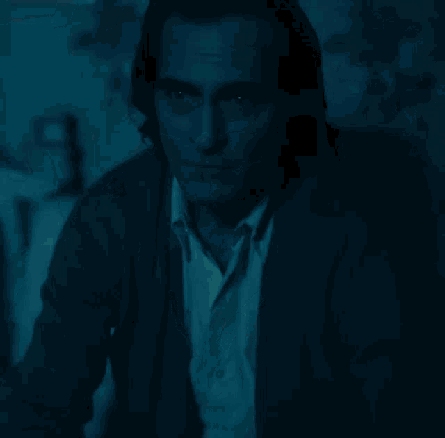 a close up of a man 's face in a dark room in a blue light .