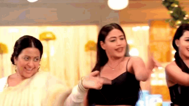 a group of women are dancing together in a room . one of the women is wearing a black top .