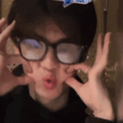 a person wearing glasses making a funny face with their hands