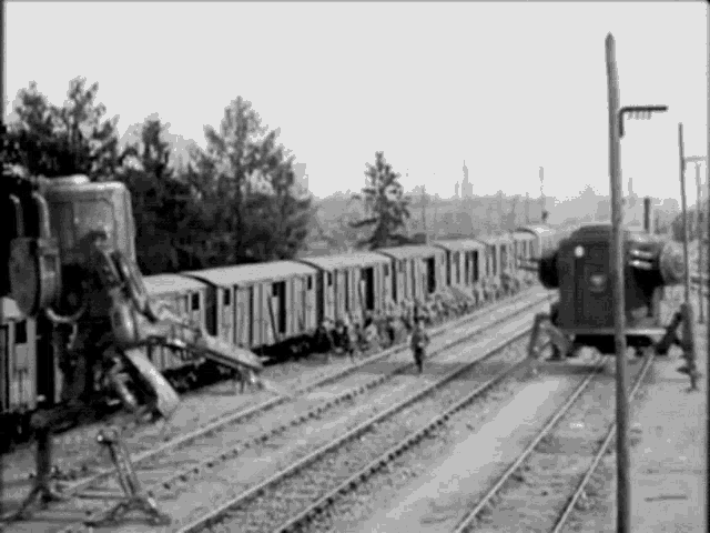 a black and white photo of a train going down the tracks .