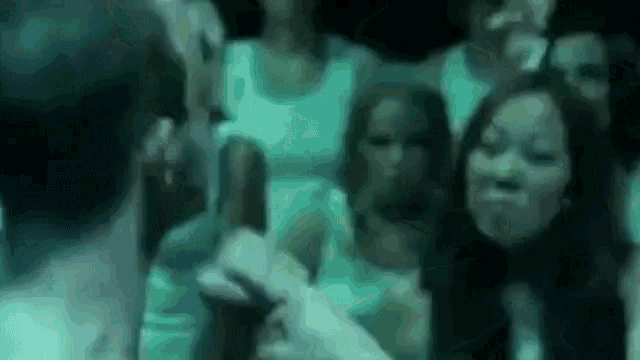 a group of people are standing in a dark room and looking at each other .