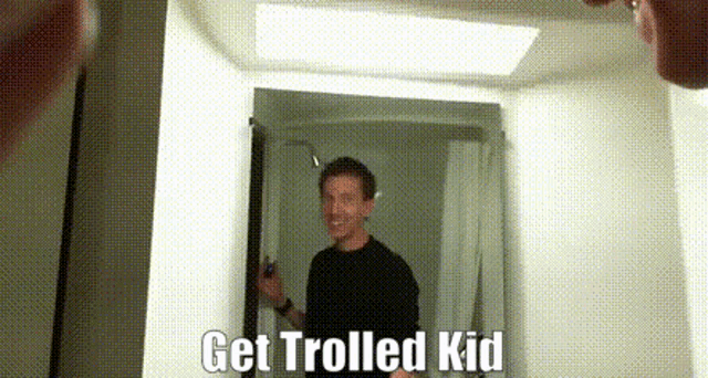 a man is standing in front of a mirror with the words get trolled kid written below him .