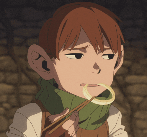 a boy with a green scarf around his neck is eating a piece of food with chopsticks