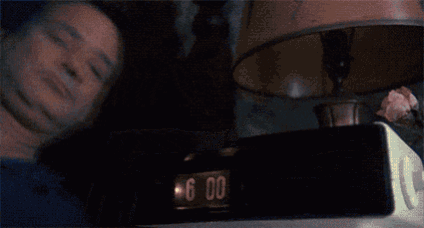 a man is covering his face while looking at a clock that says 6:00