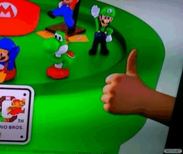a person is giving a thumbs up in front of a table with mario and luigi figurines on it .