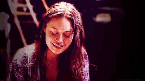 a woman is smiling with her eyes closed in a dark room with a purple background