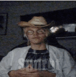 a man wearing a cowboy hat and glasses is sitting in front of a sign that says start