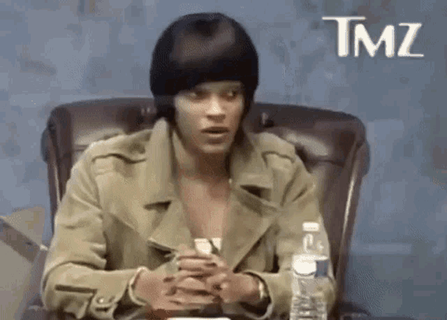 a woman is sitting in a chair with a bottle of water and a beanie on her head .