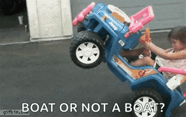 a little girl is sitting in a toy jeep that looks like a boat