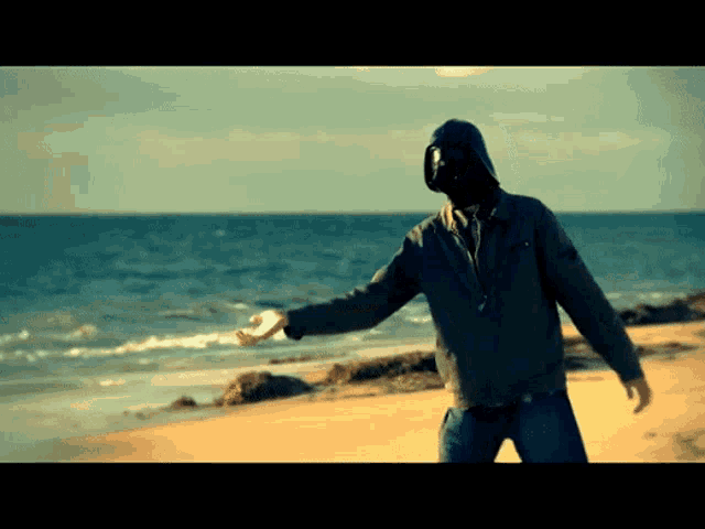 a man in a hooded jacket is standing on the beach