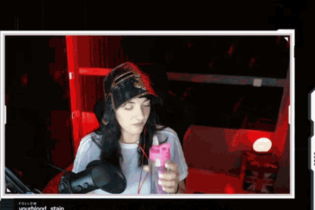 a woman wearing a hat stands in front of a microphone with the words follow yourblood stain on the bottom right