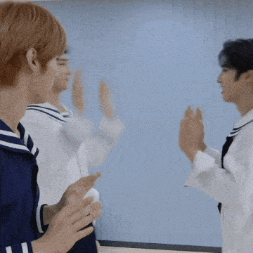a group of young men are clapping their hands in a room