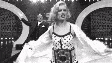 a man in a tuxedo and a woman in a polka dot dress are on a stage