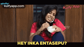 a woman in a red shirt is talking on a cell phone while holding a bowl of food