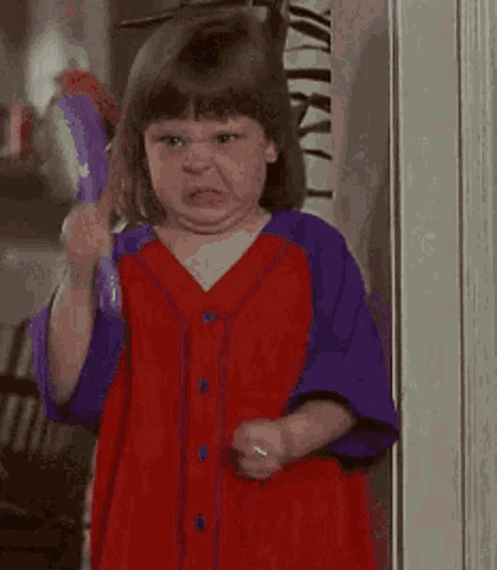 a little girl is making a funny face while holding a broom .