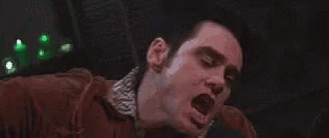 a close up of a man making a funny face while holding a microphone in a dark room .