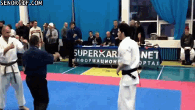 two karate fighters are fighting in front of a superkarate net sign