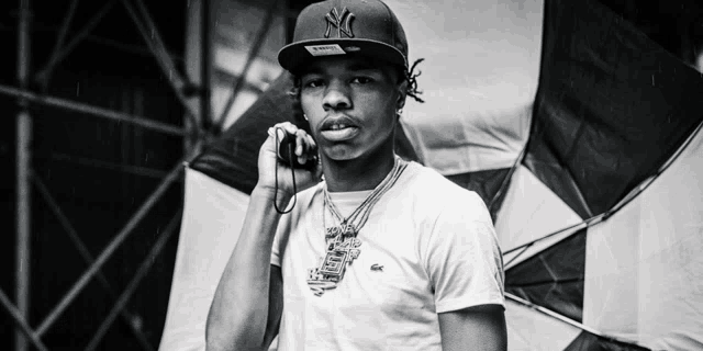 a black and white photo of a young man wearing a ny hat talking on a cell phone