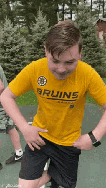 a young boy wearing a yellow bruins shirt