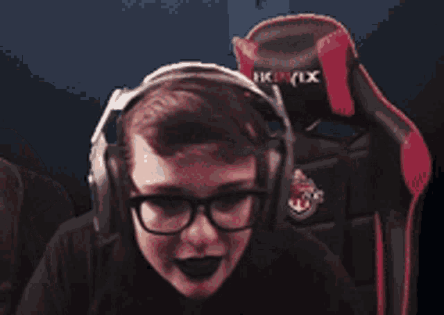 a man wearing headphones and glasses is dancing in a dark room .