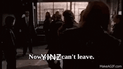 a man in a suit and tie is standing in front of a window and says `` now you can 't leave . ''