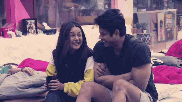 a man and a woman are sitting next to each other and laughing