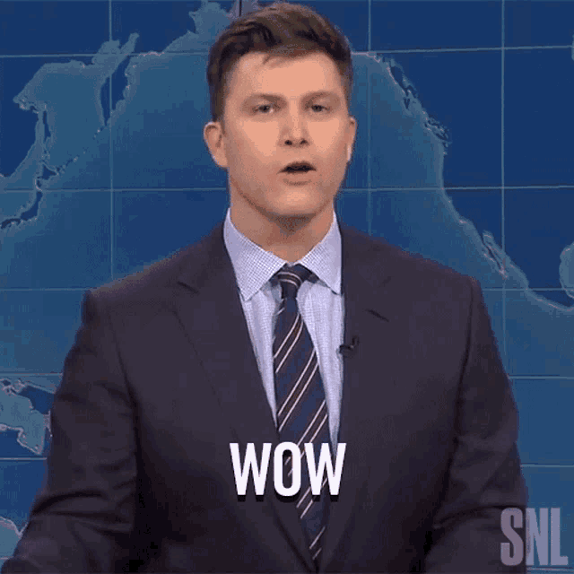 a man in a suit and tie is saying wow in front of a map of the world