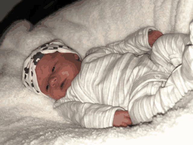 a baby wearing a striped outfit and a pink hat