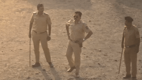 a group of police officers are standing on a dirt field