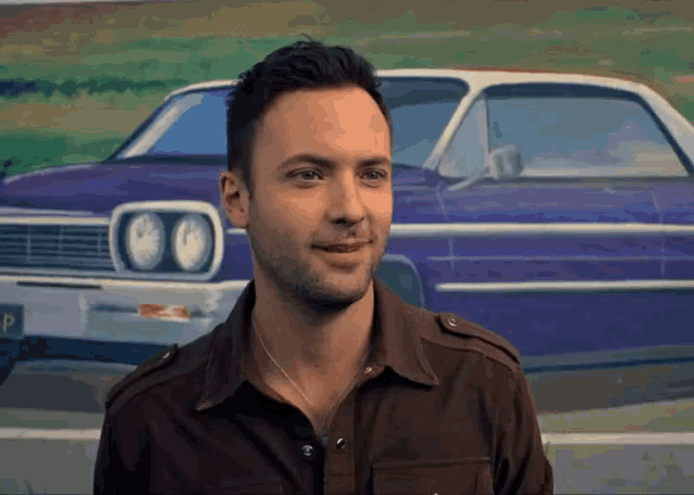 a man standing in front of a purple car with a license plate that says p
