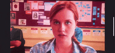 a woman with red hair is sitting in front of a bulletin board