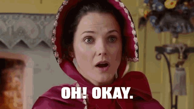 a woman wearing a red cape and a red hood is saying oh okay .