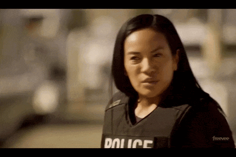 a woman wearing a police vest is standing in front of a car .