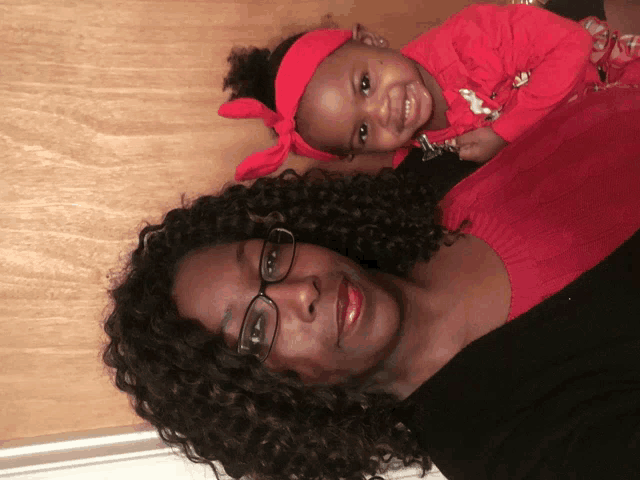 a woman with glasses holds a little girl in a red headband