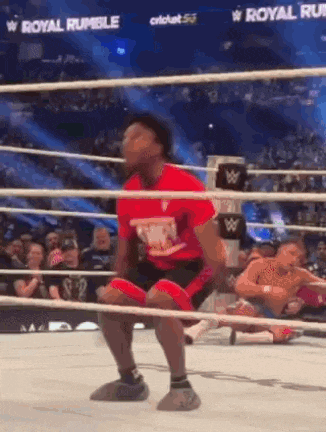 a man in a red shirt is squatting in a boxing ring .