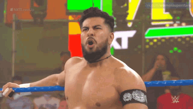 a shirtless wrestler in a ring with the word kt on the bottom right