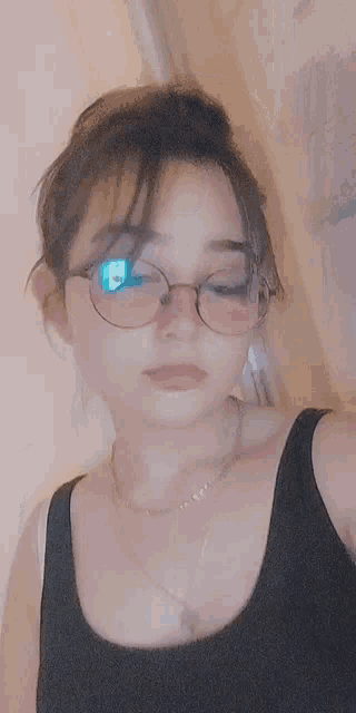 the girl is wearing glasses and a black tank top .