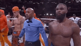three men are standing in a boxing ring with a referee .