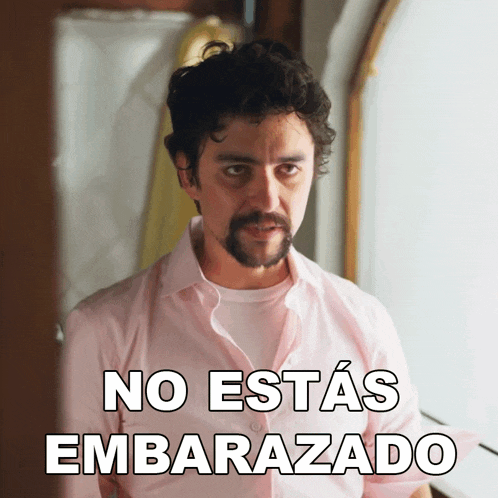 a man in a pink shirt has the words no estas embarazado on his shirt