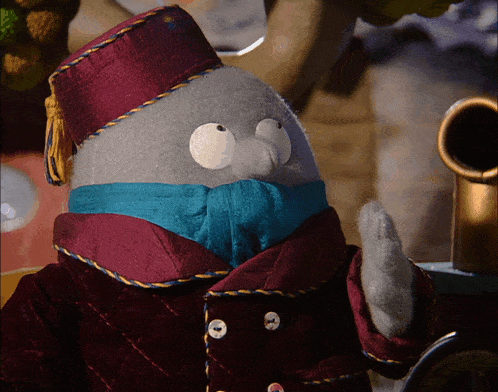 a stuffed animal wearing a red coat and a purple hat