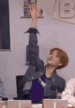 a person is sitting at a table with their hand up in the air .
