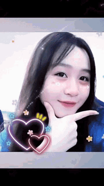 a girl with long hair is pointing to her face