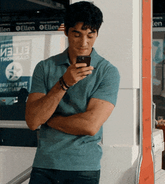 a man is looking at his phone in front of a sign that says texas supports ellen