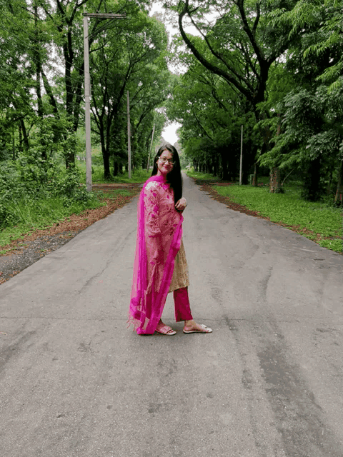 a woman in a pink dress stands on a road