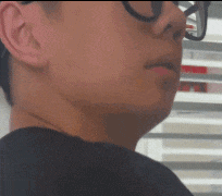 a man wearing glasses and a black shirt looks at something