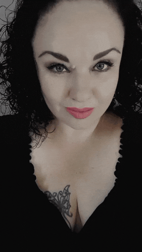 a close up of a woman 's face with a tattoo on her chest