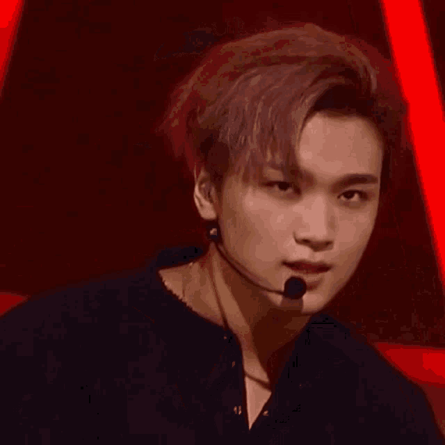 a close up of a young man wearing a microphone and a black shirt on a stage .