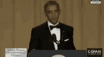 a man in a tuxedo is standing at a podium with a sign that says c-span