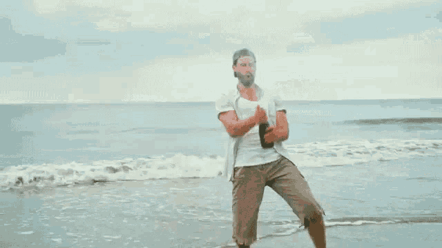 a man is running on the beach holding a bottle of beer .